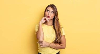 Asyalı güzel kadın düşünceli, meraklı ya da hayal kuruyor, hayal kuruyor ve uzayı kopyalamak için yukarı bakıyor.