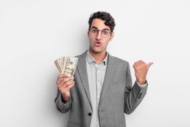 İspanyol yakışıklı adam, inançsızlıktan şaşkın şaşkın bakıyor. iş ve dolar banknotları kavramı