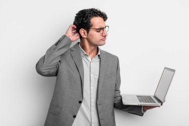 İspanyol yakışıklı adam mutlu bir şekilde gülümsüyor ve hayal kuruyor ya da şüphe ediyor. iş ve dizüstü bilgisayar kavramı