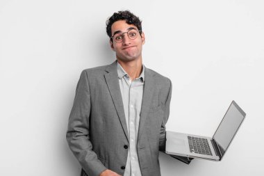 İspanyol yakışıklı adam omuz silkiyor, kafası karışık ve kararsız. iş ve dizüstü bilgisayar kavramı