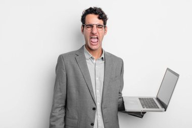 İspanyol yakışıklı adam agresif bir şekilde bağırıyor, çok kızgın görünüyor. iş ve dizüstü bilgisayar kavramı