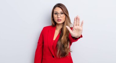 Asyalı güzel kadın ciddi görünüyor. Avuç içini gösteriyor. Durdurma hareketi yapıyor. iş kavramı