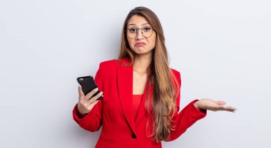 Asyalı güzel kadın şaşkın, şaşkın ve şüpheci hissediyor. iş ve telefon kavramı.