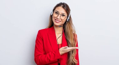 Asyalı güzel kadın neşeyle gülümsüyor, mutlu hissediyor ve bir konsept gösteriyor. tele pazarlamacı kavramı