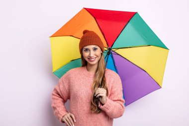 Asyalı güzel kadın mutlu bir şekilde gülümsüyor, eli kalçasında ve kendinden emin. şemsiye kavramı