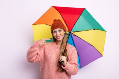 Asyalı güzel bir kadın, kendine güvenerek kendi gülümsemesine işaret ediyor. şemsiye kavramı