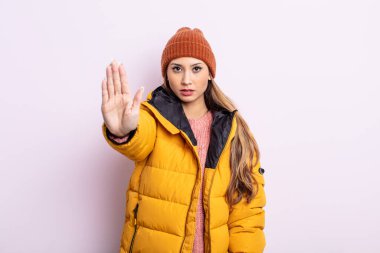 Asyalı güzel kadın ciddi görünüyor. Avuç içini gösteriyor. Durdurma hareketi yapıyor. kış konsepti