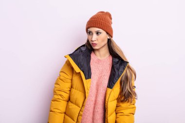 Asyalı güzel kadın üzgün, üzgün ya da kızgın hissediyor ve yan tarafa bakıyor. kış konsepti