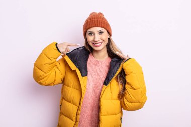 Asyalı güzel bir kadın, kendine güvenerek kendi gülümsemesine işaret ediyor. kış konsepti