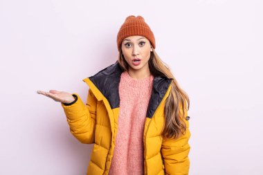 Asyalı güzel kadın şaşırmış ve şok olmuş görünüyor. Çenesi düşmüş ve elinde bir nesne var. kış konsepti