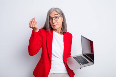 Kıdemli güzel kadın kapiş ya da para hareketi yapıyor, sana ödemeni söylüyor. iş ve dizüstü bilgisayar kavramı