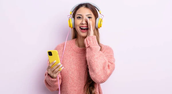 アジア系の可愛い女性は幸せを感じ口の横で大きな声を出す ヘッドフォンと電話のコンセプト — ストック写真