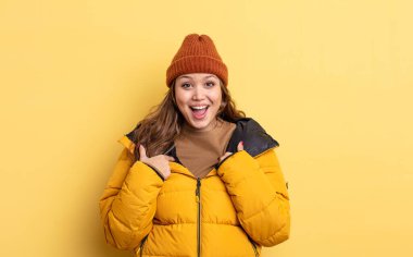 İspanyol güzel kadın kendini mutlu hissediyor ve heyecanla kendini işaret ediyor. Kış giysileri