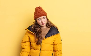 Hispanik güzel kadın üzgün, üzgün ya da kızgın hissediyor ve yana bakıyor. Kış giysileri