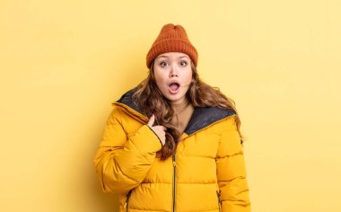 İspanyol güzel kadın şok olmuş ve ağzı açık bir şekilde kendini işaret ederek şaşırmış görünüyor. Kış giysileri