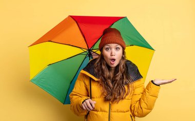 İspanyol güzel kadın şaşırmış ve şok olmuş görünüyor. Çenesi düşmüş ve elinde bir nesne var. şemsiye kavramı