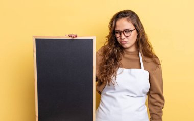 Hispanik güzel kadın üzgün, üzgün ya da kızgın hissediyor ve yana bakıyor. Tahta kopyalama alanı kavramı