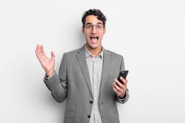 İspanyol yakışıklı adam kendini mutlu hissediyor ve inanılmaz bir şeye hayret ediyor. iş ve telefon kavramı