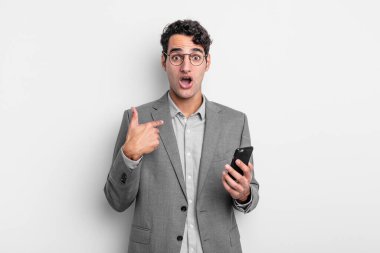 İspanyol yakışıklı adam mutlu hissediyor ve heyecanla kendini işaret ediyor. iş ve telefon kavramı