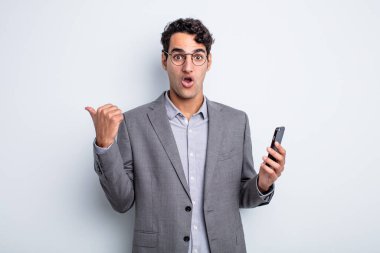 İspanyol yakışıklı adam, inançsızlıktan şaşkın şaşkın bakıyor. iş ve telefon kavramı