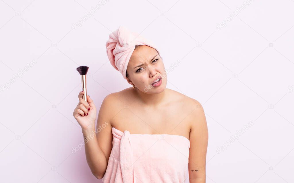 hispanic pretty woman feeling puzzled and confused. make up brush concept