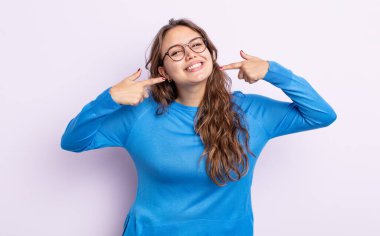 İspanyol güzel kadın kendine güvenerek gülümsüyor. Geniş gülümseme, pozitif, rahat, tatmin olmuş tavır.