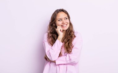 İspanyol güzel kadın mutlu bir şekilde gülümsüyor ve hayal kuruyor ya da şüphe ediyor, yan tarafa bakıyor.