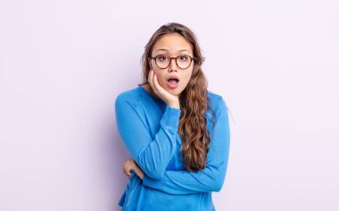 İspanyol güzel kadın şok ve inançsızlık içinde ağzı açık, elleri yanağında ve kolları çaprazlanmış, sersemlemiş ve şaşırmış hissediyor