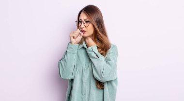 Asyalı güzel bir kadın boğazı ağrıyan ve grip belirtileri gösteren ağzı kapalı öksüren bir hasta.