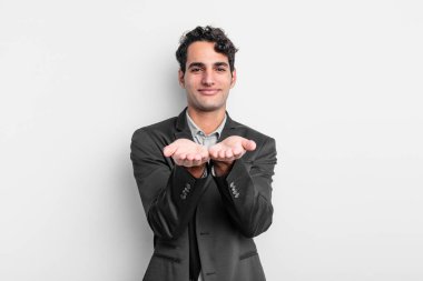 Genç işadamı mutlu bir şekilde gülümsüyor, kendine güvenen, olumlu bakan, bir nesne ya da konsept sunan ve gösteren