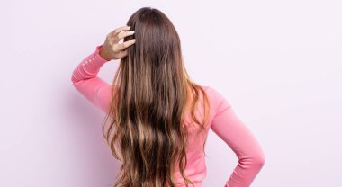 Asyalı güzel kadın bilgisiz ve kafası karışık hissediyor, bir çözüm düşünüyor, eli kalçasında, diğeri kafasında, dikiz aynasından.