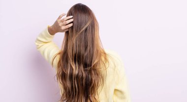 Asyalı güzel kadın düşünüyor ya da şüphe ediyor, kafasını kaşıyor, kafası karışık ve kafası karışık hissediyor, arkaya ya da arkaya bakıyor.