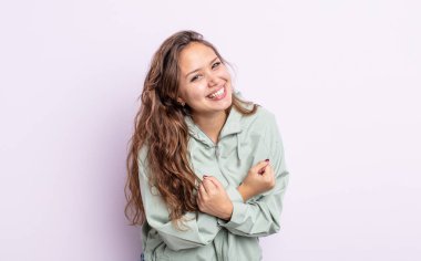 İspanyol güzel kadın neşeli bir şekilde gülümsüyor ve kutluyor, yumruklarını sıkıp kollarını kavuşturuyor, mutlu ve pozitif hissediyor.