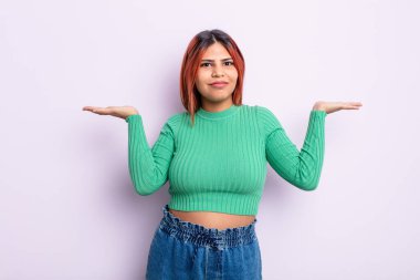 Genç İspanyol kadın şaşkın ve kafası karışık, şüpheci, farklı seçenekleri tartıyor veya komik bir ifadeyle seçiyor.