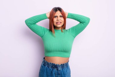 Genç İspanyol kadın kendini stresli, endişeli, endişeli ya da korkmuş hissediyor. Elleri başının üstünde, hatayla panikliyor.