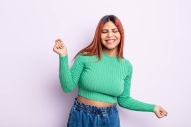 Genç İspanyol kadın gülümsüyor, kaygısız hissediyor, rahat ve mutlu, dans ediyor ve müzik dinliyor, bir partide eğleniyor.