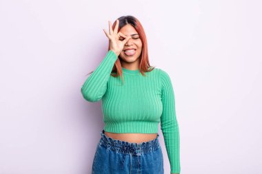 Genç İspanyol kadın mutlu bir şekilde gülümsüyor, şaka yapıyor ve gözetleme deliğinden bakıyor, sırları gözetliyor.