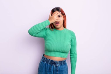 Genç İspanyol kadın şok olmuş, korkmuş ya da korkmuş görünüyor. Yüzü elle kaplanmış ve parmaklarının arasından gizlice bakıyor.