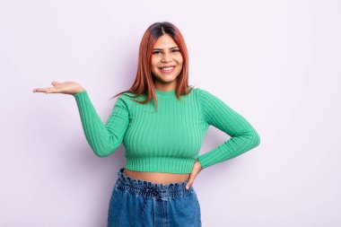 Genç İspanyol kadın gülümsüyor, kendinden emin, başarılı ve mutlu hissediyor, fotokopi alanında fikir veya konsept gösteriyor.