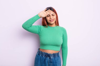 Genç İspanyol kadın stresli, yorgun ve hayal kırıklığına uğramış görünüyor, alnından ter damlıyor, umutsuz ve bitkin hissediyor.