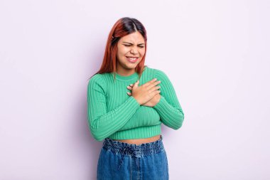 Genç İspanyol kadın üzgün, yaralı ve kalbi kırık görünüyor, iki elini de kalbe yakın tutuyor, ağlıyor ve bunalımda.