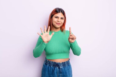 Genç İspanyol kadın gülümsüyor ve arkadaş canlısı görünüyor, 6 ya da 6 numarayı gösteriyor, elleri önde, geriye doğru sayıyor.