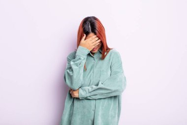 Genç İspanyol kadın stresli, utanmış ya da üzgün görünüyor, baş ağrısı var, yüzünü eliyle kapatıyor.