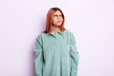 Genç İspanyol kadın şaşkın ve şaşkın görünüyor, merak ediyor veya bir sorunu çözmeye çalışıyor veya düşünüyor.