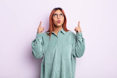 Genç İspanyol kadın şaşkınlık içinde ve ağzı açık. Şok olmuş ve şaşırmış bir bakışla yukarı bakıyor.