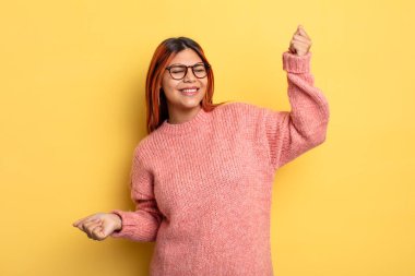 Genç İspanyol kadın gülümsüyor, kaygısız hissediyor, rahat ve mutlu, dans ediyor ve müzik dinliyor, bir partide eğleniyor.