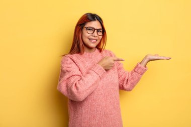 Genç İspanyol kadın gülümsüyor, mutlu, kaygısız ve tatmin olmuş hissediyor, fotokopi alanındaki konsepte ya da fikre işaret ediyor.
