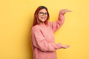 Genç İspanyol kadın gülümsüyor, mutlu, pozitif ve memnun, fotokopi alanında nesne ya da konsept tutuyor ya da gösteriyor