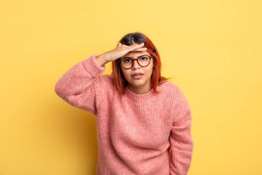 Genç İspanyol kadın şaşkınlık ve şaşkınlık içinde bakıyor, el üstünde uzak bakıyor, izliyor ya da arıyor.