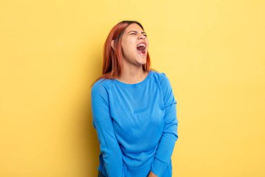 Genç İspanyol kadın öfkeyle bağırıyor, agresif bir şekilde bağırıyor, stresli ve kızgın görünüyor.